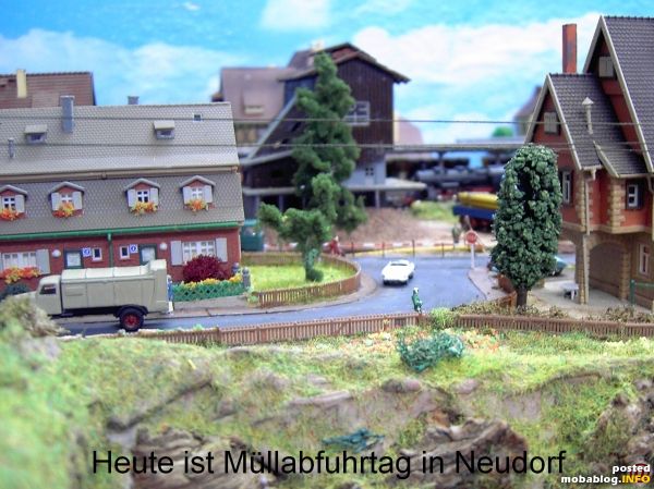 Blick aus dem Schienenbus auf Neudorf mit im Hintergrund befindlichem Bahnhof und Müllabfuhr im Vorfergrund