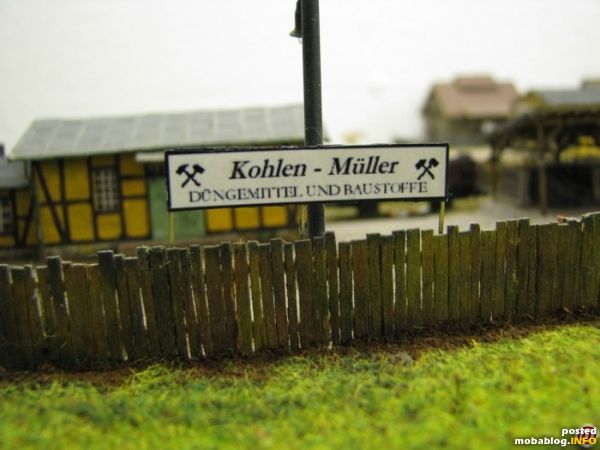 Ein Bretterzaun umgibt das Objekt. Die Bretter bestehen aus dünnen Furnierstreifen die einzeln auf sehr dünne Leistchen aufgeklebt wurden.