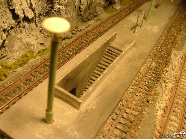 Gäbe es echte Menschen mit 12 mm Körpergröße, könnten die vorbildgerecht die Gleise unterqueren. Treppen und Geländer sind funktionstüchtig montiert. Leider hat sich der Weißleim im Gleisschotter im Laufe der ...
