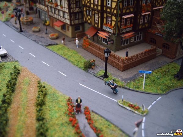 Im Vordergrund geht Oma Erna mit ihrer Gehhilfe ;-) Auf der anderen Strassenseite erkennt man Bäcker Meier vor seinem Geschäft, auf Kundschaft wartend. Am Strassenrand beobachtet eine Touristin den verrückten ...