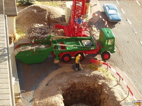 Mit Bauschutt beladene Mulde wird abgeholt, einhängen der Mulde am Tragarm