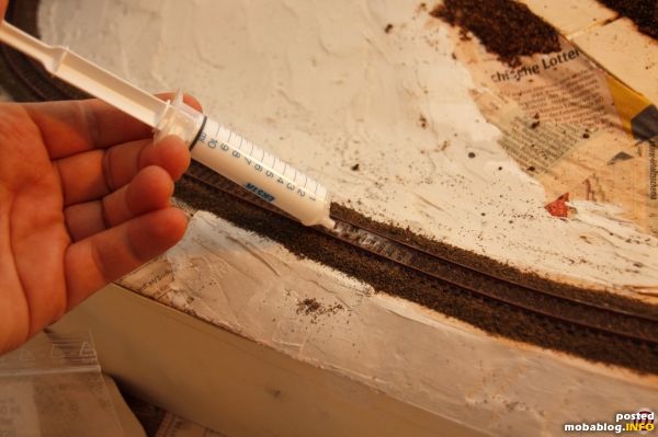 Der eingefeuchtete Schotter kann sodann mit Leim-Wasser-Spülmittelgemisch getränkt werden. Ich gehe einmal über das Schwellenbett, dann werden die linke und dann die rechte Seite getränkt.