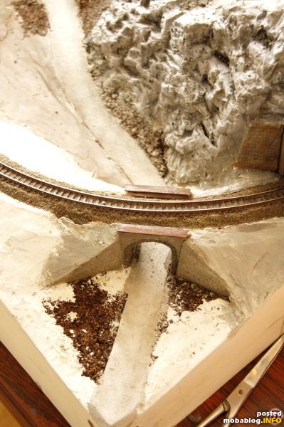 Straße - Gleise - Brücke - Felsen, das klassische Motiv der Minianlage kurz vor dem Einzug des ersten Grünzeugs. Die Überführung ist auch schon eingefärbt und mit Abdeckungen aus dünnem ...