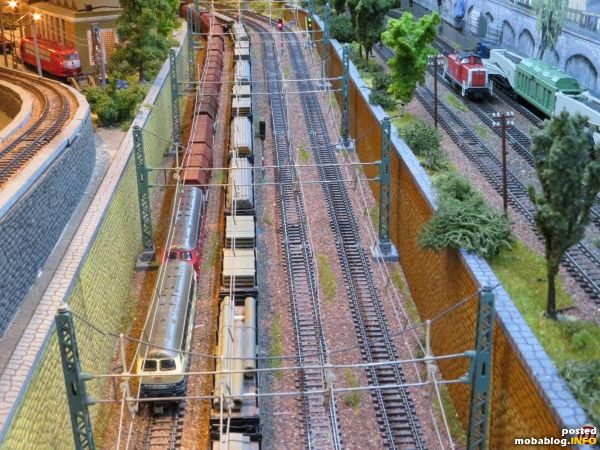 Auf der Rampe begegnen die beiden 216 mit ihren Teleskophaubenwagen einen Stahlzug. Die 103 im BW hat einen Unfallschaden und wurde bereits z-gestellt. Auf der Nebenstrecke passiert eine 212 als ...