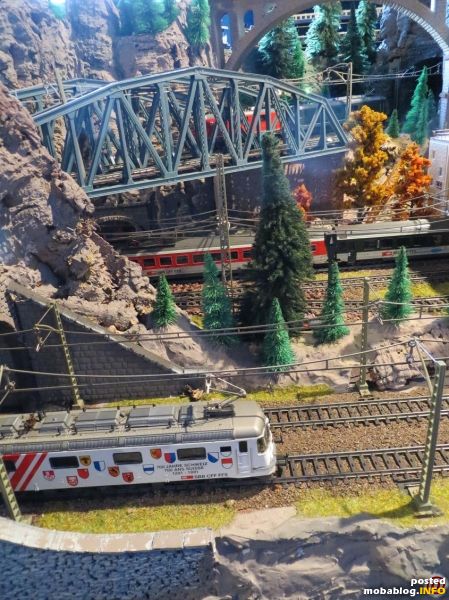 Auf den Kehren der Südrampe begegnen sich eine Re 10/10 auf der Brücke mit einem Schnellzug aus EW IV-Wagen und der