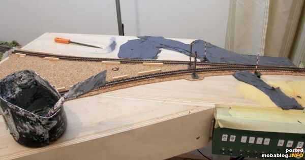 Der Bahnübergang noch im Rohbau. Die Staße entstand aus gefärbter Spachtelmasse, hier noch grob aufgetragen. Unten sieht man das
elektromechanischen Stellwerk http://www.mobablog.info/blog.php?id=1823