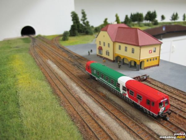 Enzersdorf-Staatz ist ein Abzweigbahnhof - ein StLB-Triebwagen hält vor dem Aufnahmsgebäude - im Hintergrund zweigt die Strecke rechts in Richtung Türnitz ab, während die gerade Strecke in einem Tunnel verschwindet, ...