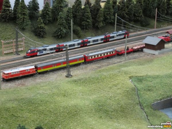 Viel Betrieb in Breitenstein: der planmäßige Regional-Triebwagen Reihe 4024 Talent hält in der Station, während am Ladegleis ein langer Bauzug auf den nächsten Einsatz wartet