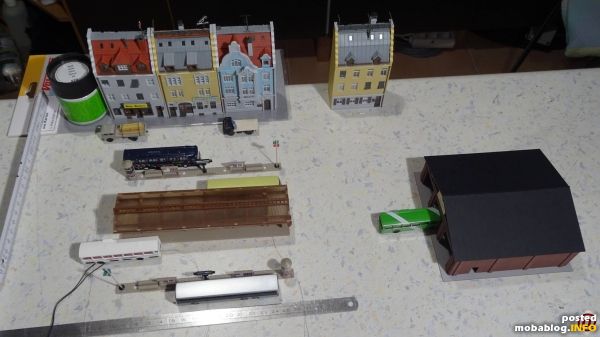 Eine erste Stellprobe auf der Arbeitsplatte.
Die Löcher für die Lampen in den Busbahnsteigen sind schon gebohrt.
Hier werden die Vissmann Lampen eingesetzt.
Fahnenmaste und Litfass-Säulen sind aus dem Fundus.
Die selbstgedruckten Ortsschilder an ...
