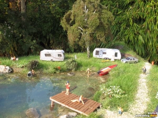 Ein kleiner Badesteg rundet den Uferbereich ab, einige Wohnwagen-Camper genießen die freie Sicht auf den See