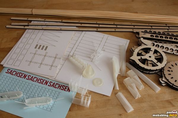 Hier die Teile zur Montage. Erkennbar die hölzernen Teile für das Spantengerüst, gelaserte Kartonteile der Aussenhaut, 3D Druckteile für Gondeln, Ruderanlage, Bug und Heck sowie komplizierter Teile des Kiels. Decals ...