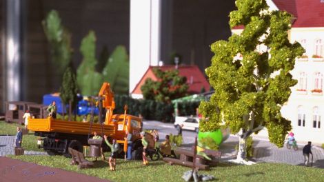 Die Stadtverwaltung entlädt grade robust gebaute Bänke und Tische, die von Pfandfindern nahe dem schatten spendeten Baum aufgestellt werden.